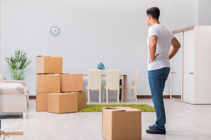 man frustrated by moving boxes alone